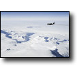 A ski-equipped C-130 Hercules flies over the Transantarctic Mountains en route to McMurdo from the South Pole. (MCM)